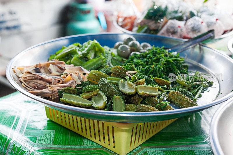 在Damnoen Saduak水上市场的船上出售的一盘熟蔬菜。泰国